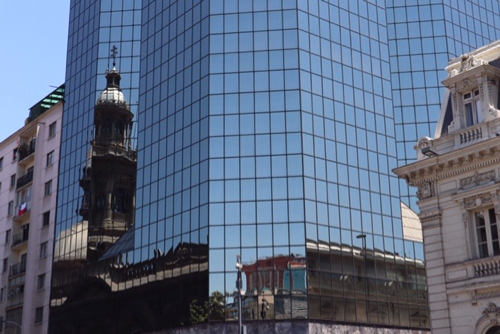 A reflective glass building, The reflection of the city building shows a historic tower reflected in the modern black window in Santiago Chile