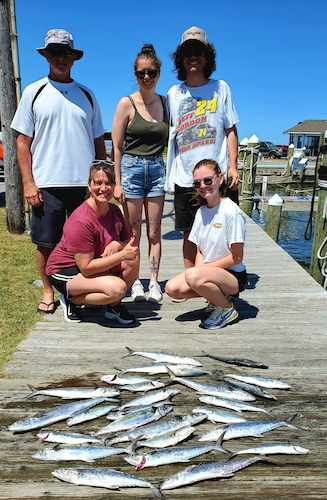 family of five persons on the dock with their catch of spanish mackeral.