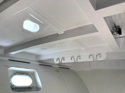 picture of the white new paint reflecting the sunshine through the porthole. Overhead of the v bunk area where we store our rods. 