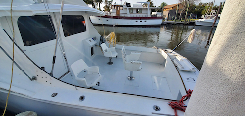 all white cockpit of the boat sinbad. it has three chairs, clean white deck and is sitting side to at the dock. 